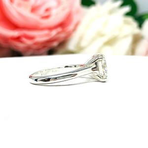 Sterling silver 8mm near colorless (G/H color) asscher cut cubic zirconia solitaire engagement ring. The ring is resting on a white surface with a background of pink and white flowers.