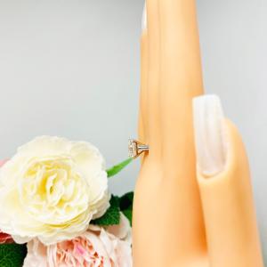 Mannequin hand with long white shimmery nails, displayed against a soft white-gray background with pink and white floral accents. The hand is wearing a sterling silver 9mm near colorless (G/H color) asscher cut cubic zirconia solitaire engagement ring.