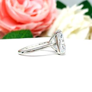 Elegant sterling silver cathedral engagement ring set with a large radiant cut cubic zirconia, beautifully photographed against a romantic and timeless soft-focus floral background of pink and white blooms.