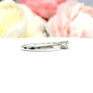 Dainty 4-prong sterling silver, horizontal east west set engagement ring featuring a precision-faceted marquise cubic zirconia.  Displayed on a white surface with soft pastel floral background.
