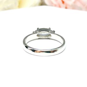 A 6-prong sterling silver, horizontal east west set engagement ring featuring a precision-faceted near colorless (G/H color) marquise cubic zirconia.  Displayed on a white surface with soft pastel floral background.