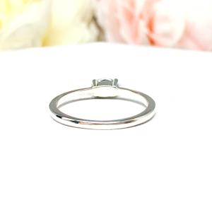 Dainty 4-prong sterling silver, horizontal east west set engagement ring featuring a precision-faceted marquise cubic zirconia.  Displayed on a white surface with soft pastel floral background.