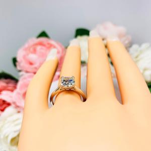 Mannequin hand with long white shimmery nails, displayed against a soft white-gray background with pink and white floral accents. The hand is wearing a sterling silver split prong cathedral engagement ring set with an 7.5mm near colorless old mine cut cubic zirconia.