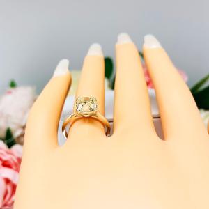 Mannequin hand with long white shimmery nails, displayed against a soft white-gray background with pink and white floral accents. The hand is wearing a sterling silver split prong cathedral engagement ring set with an 8mm light yellow old mine cut cubic zirconia.