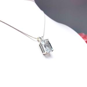 Close-up of an emerald-cut white topaz pendant necklace featuring a faceted natural gemstone in a sterling silver prong setting, suspended from a delicate sterling chain. Available in four stone sizes.