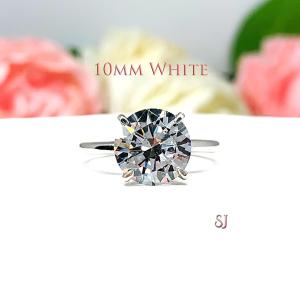 Close-up view of a near colorless (G/H color) round brilliant cut cubic zirconia solitaire ring in a claw prong cathedral setting. The ring is made of sterling silver and features a sleek, minimalist design. The setting is simple yet elegant, allowing the center stone to take center stage. The ring is displayed against a soft, blurred background of pastel-colored flowers, creating a romantic and delicate ambiance. This example is the 10mm white version.