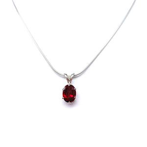 Sterling silver necklace featuring an oval lab-created ruby pendant in a six-prong setting, suspended from a thin silver chain and photographed against a white background.