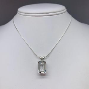 Unedited photo of an emerald-cut white topaz pendant necklace featuring a faceted natural gemstone in a sterling silver prong setting, suspended from a delicate sterling chain. Available in five stone sizes.