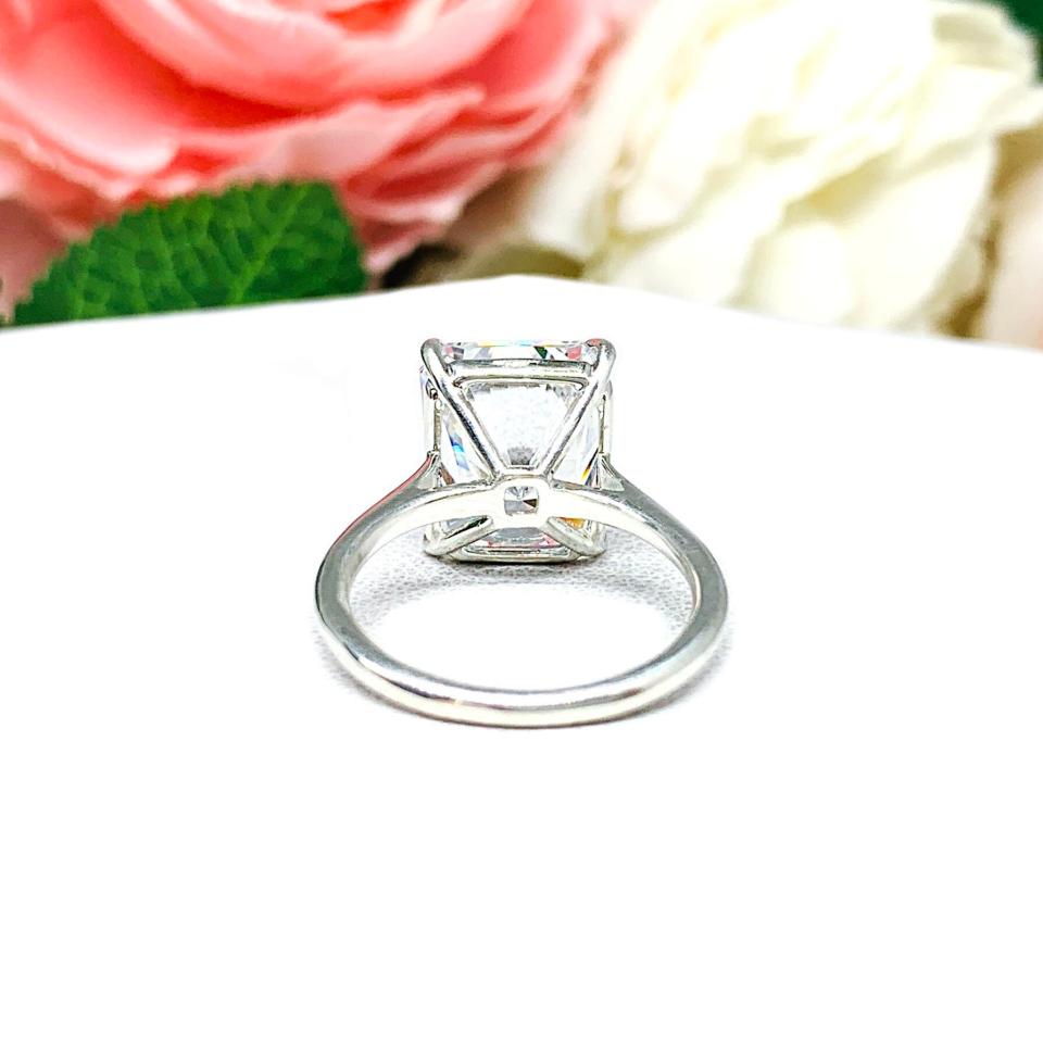 Elegant sterling silver cathedral engagement ring set with a large radiant cut cubic zirconia, beautifully photographed against a romantic and timeless soft-focus floral background of pink and white blooms.