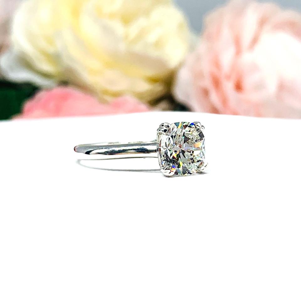 Close-up of a sterling silver cathedral-style engagement ring featuring an 8mm near colorless cushion cut cubic zirconia center stone. The ring is shown facing forward, showcasing the brilliant faceting of the center stone and split prongs.