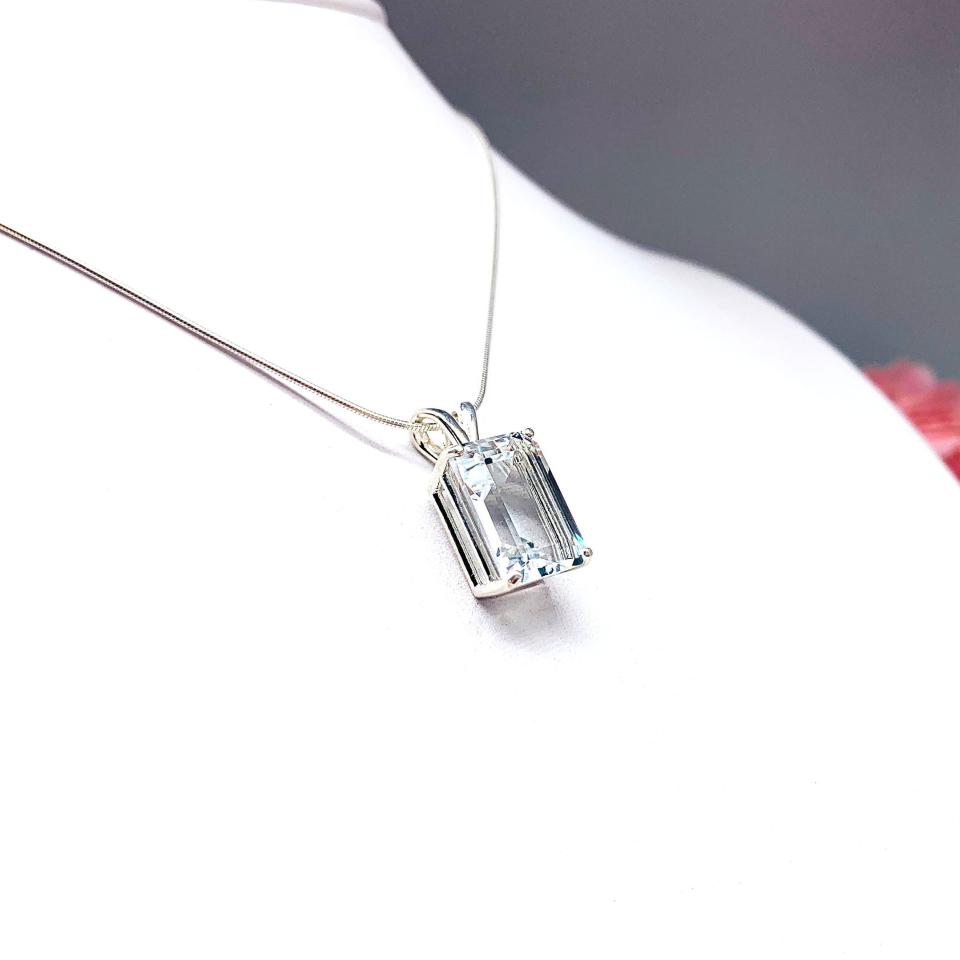 Close-up of an emerald-cut white topaz pendant necklace featuring a faceted natural gemstone in a sterling silver prong setting, suspended from a delicate sterling chain. Available in four stone sizes.