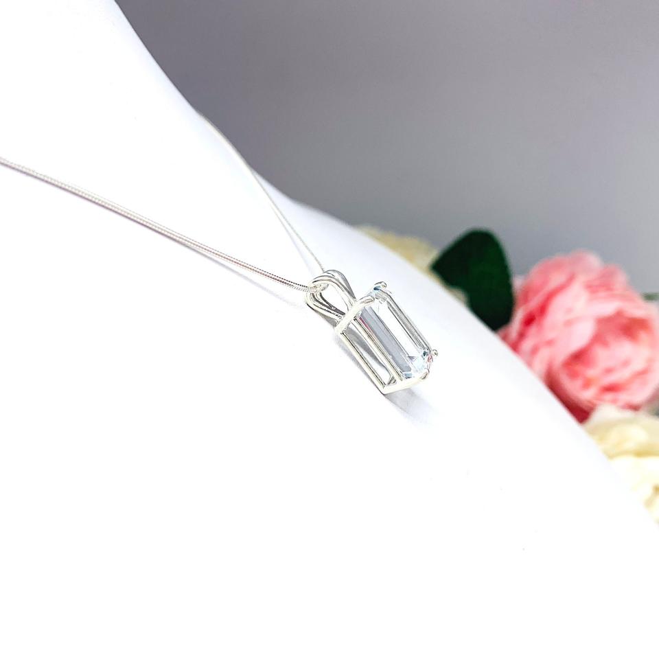 Close-up of an emerald-cut white topaz pendant necklace featuring a faceted natural gemstone in a sterling silver prong setting, suspended from a delicate sterling chain. Available in four stone sizes.