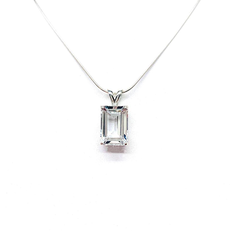 Close-up of an emerald-cut white topaz pendant necklace featuring a faceted natural gemstone in a sterling silver prong setting, suspended from a delicate sterling chain. Available in four stone sizes.