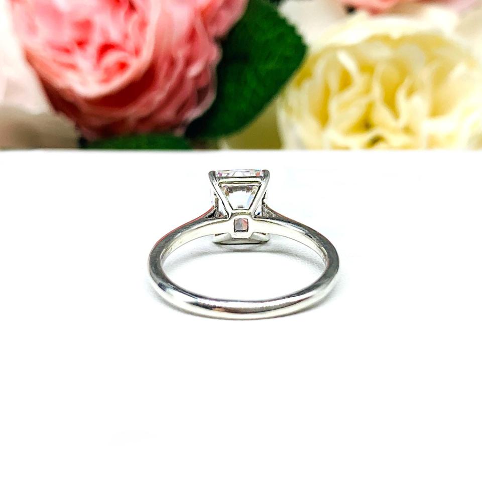 Elegant sterling silver cathedral engagement ring set with a 9x7mm radiant cut cubic zirconia, beautifully photographed against a romantic and timeless soft-focus floral background of pink and white blooms.